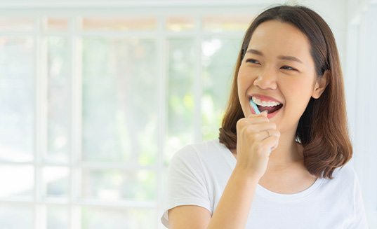 Patient in Cary brushing after successful dental implant surgery