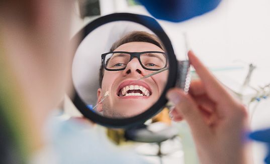 Patient in Cary checking mouth in mirror after dental implant placement