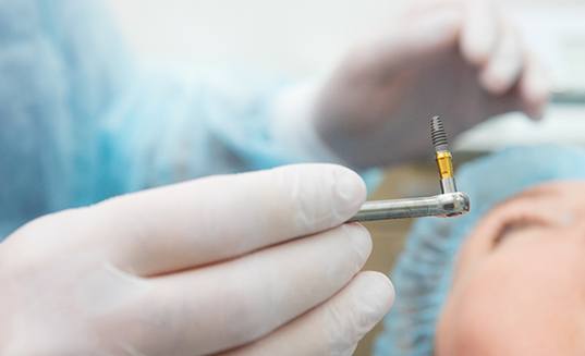 Dentist holding a single dental implant