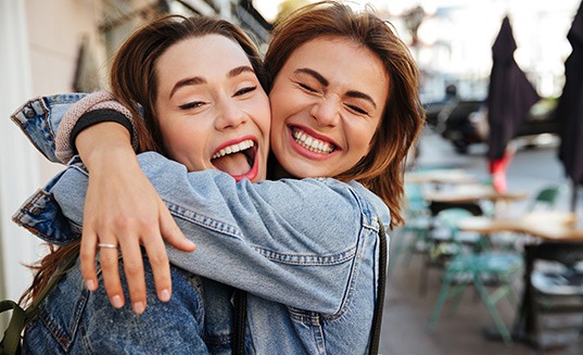 Patient in Cary smiling confidently with friend after dental implants