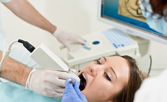 A woman getting her mouth scanned for a dental crown