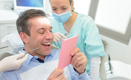 A man looking in the mirror at his dental crown