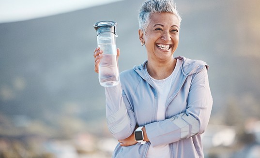 Woman smiling with water bottle on hike outside