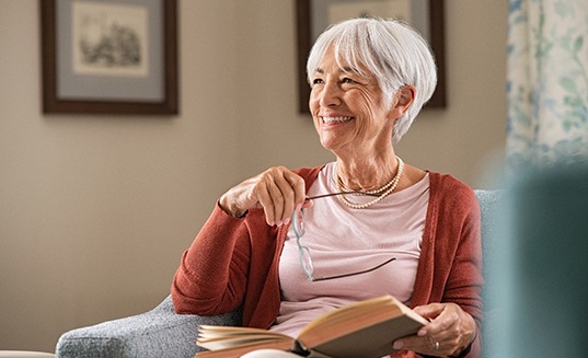 Senior woman smiling while reading at home