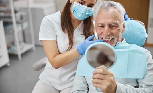 a patient sitting in a treatment chair speaking with her dentist
